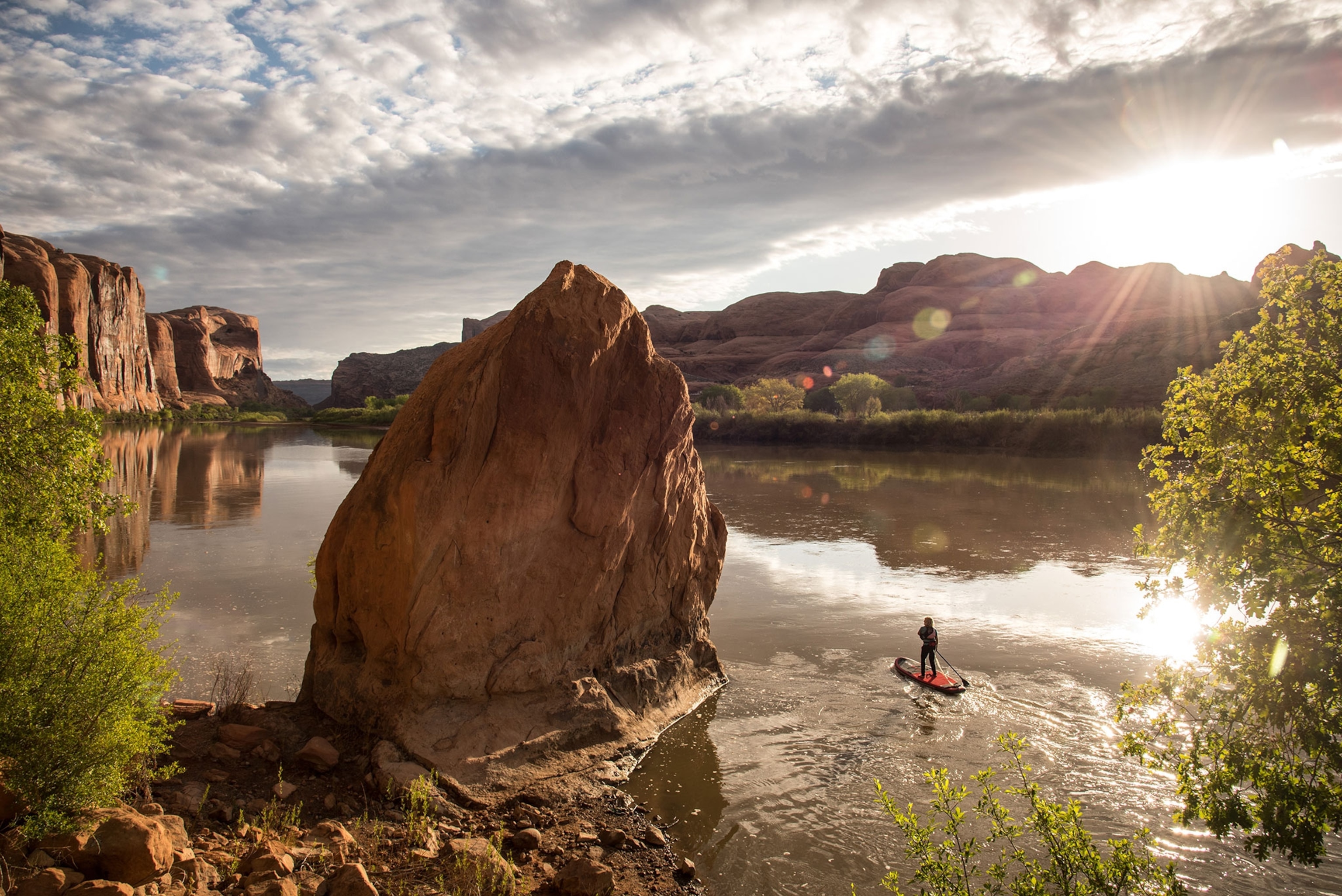 A woman navigating on a stand up paddle board on the Colorado River.