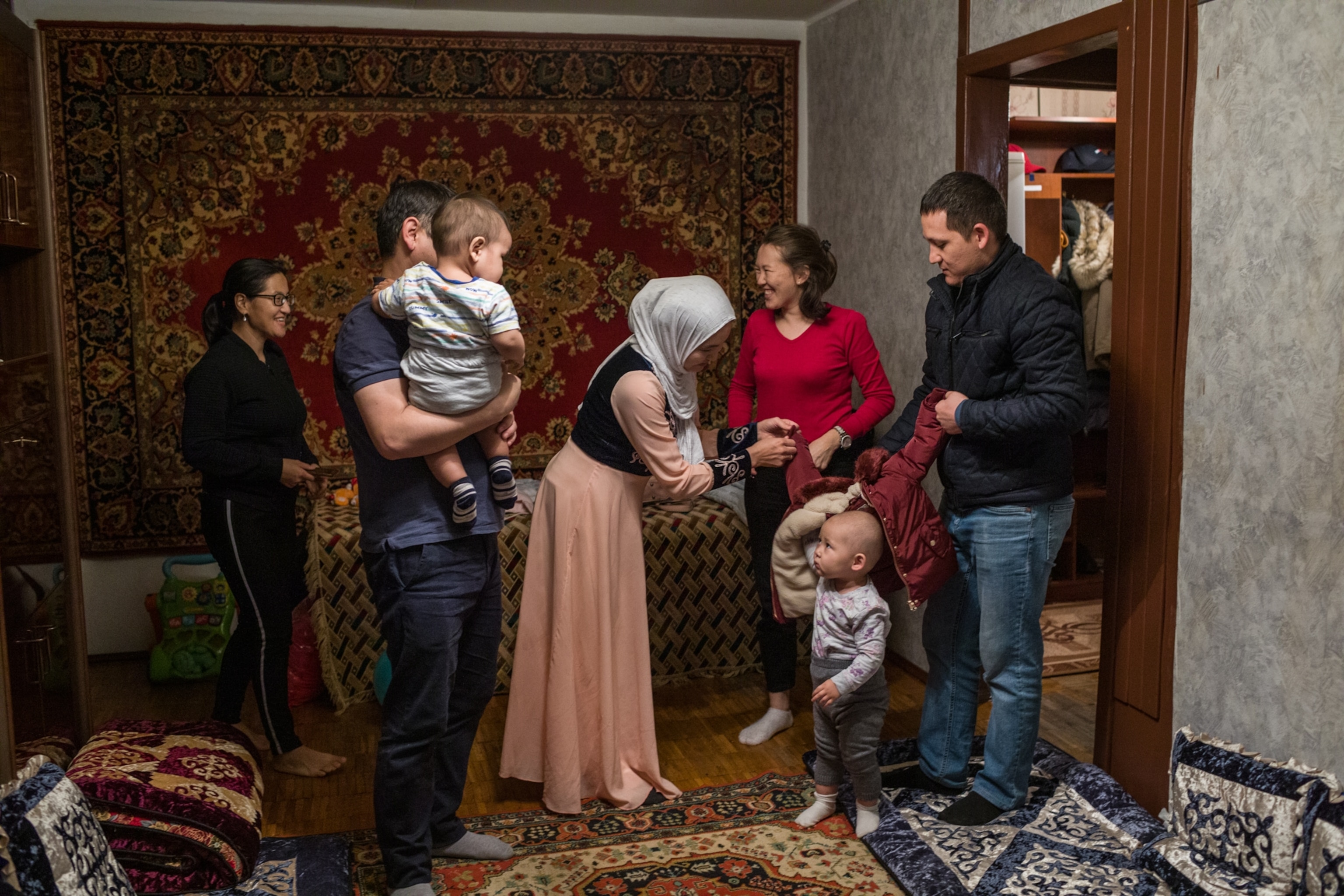 a woman and family greeting another family walking through a door