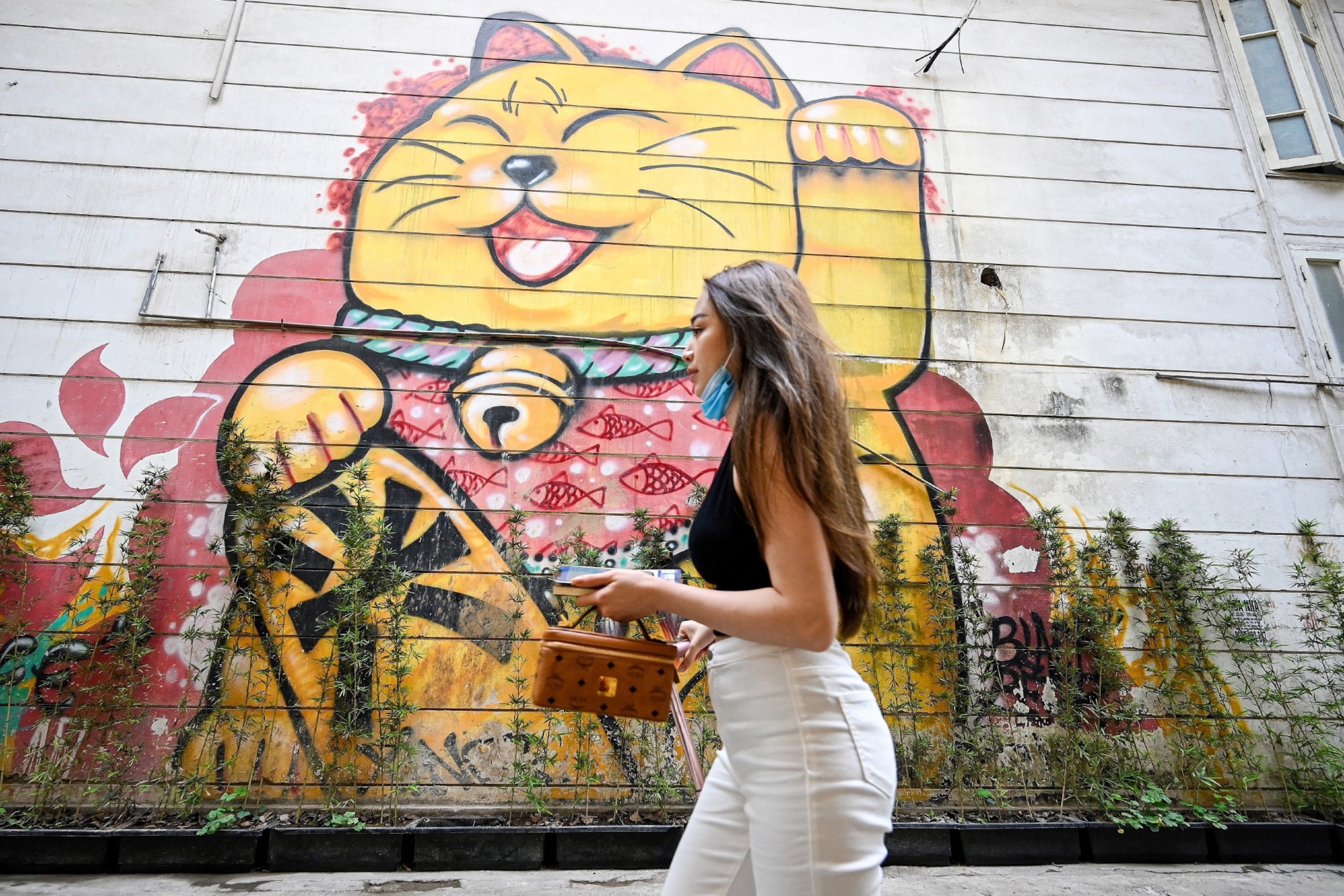 Woman walking past cat street mural
