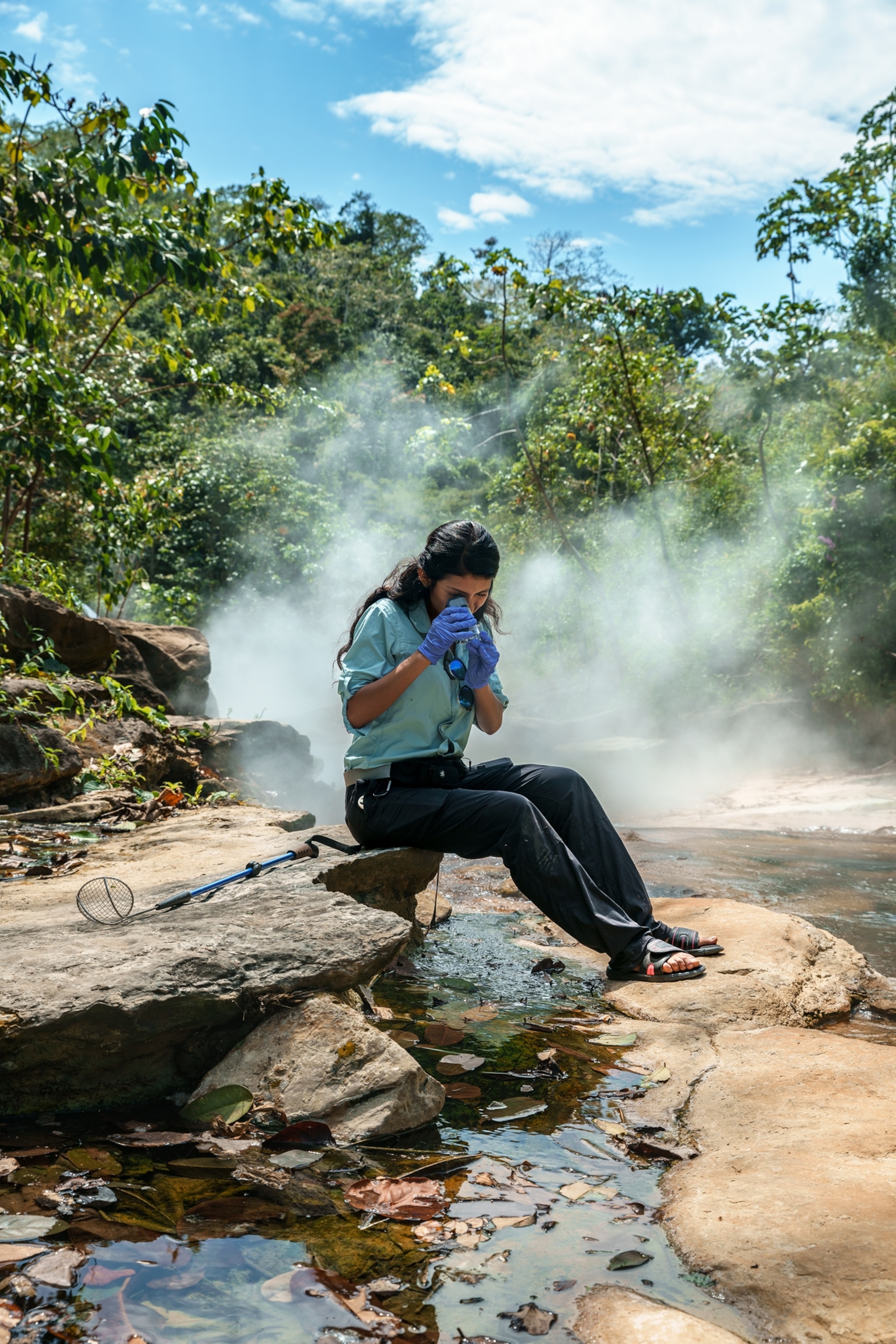 Picture of women sitting or rock and looking into field microscope.