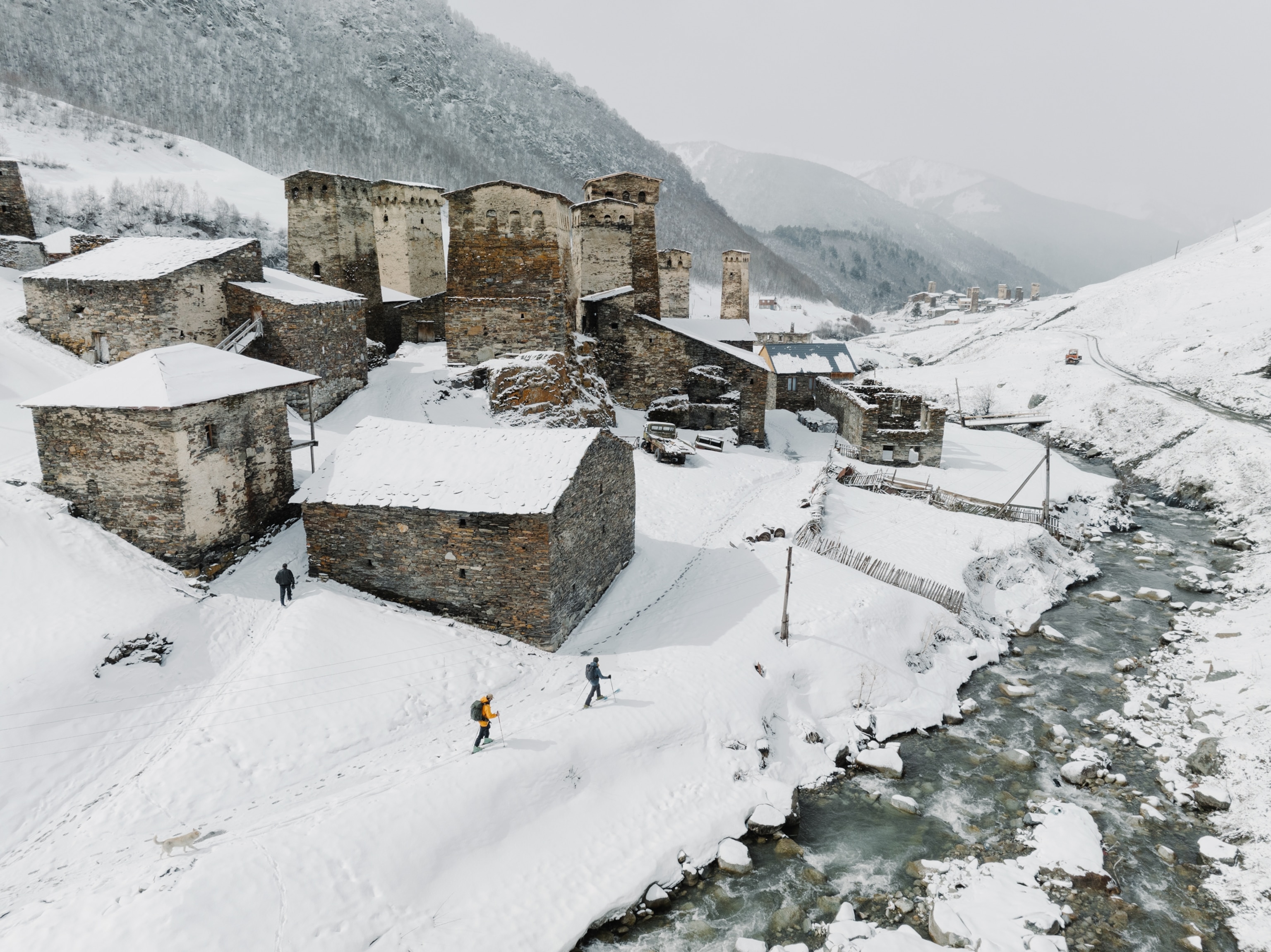 An overview of people ski touring around the towers of the Village of Chazhashi in Ushguli, Svaneti