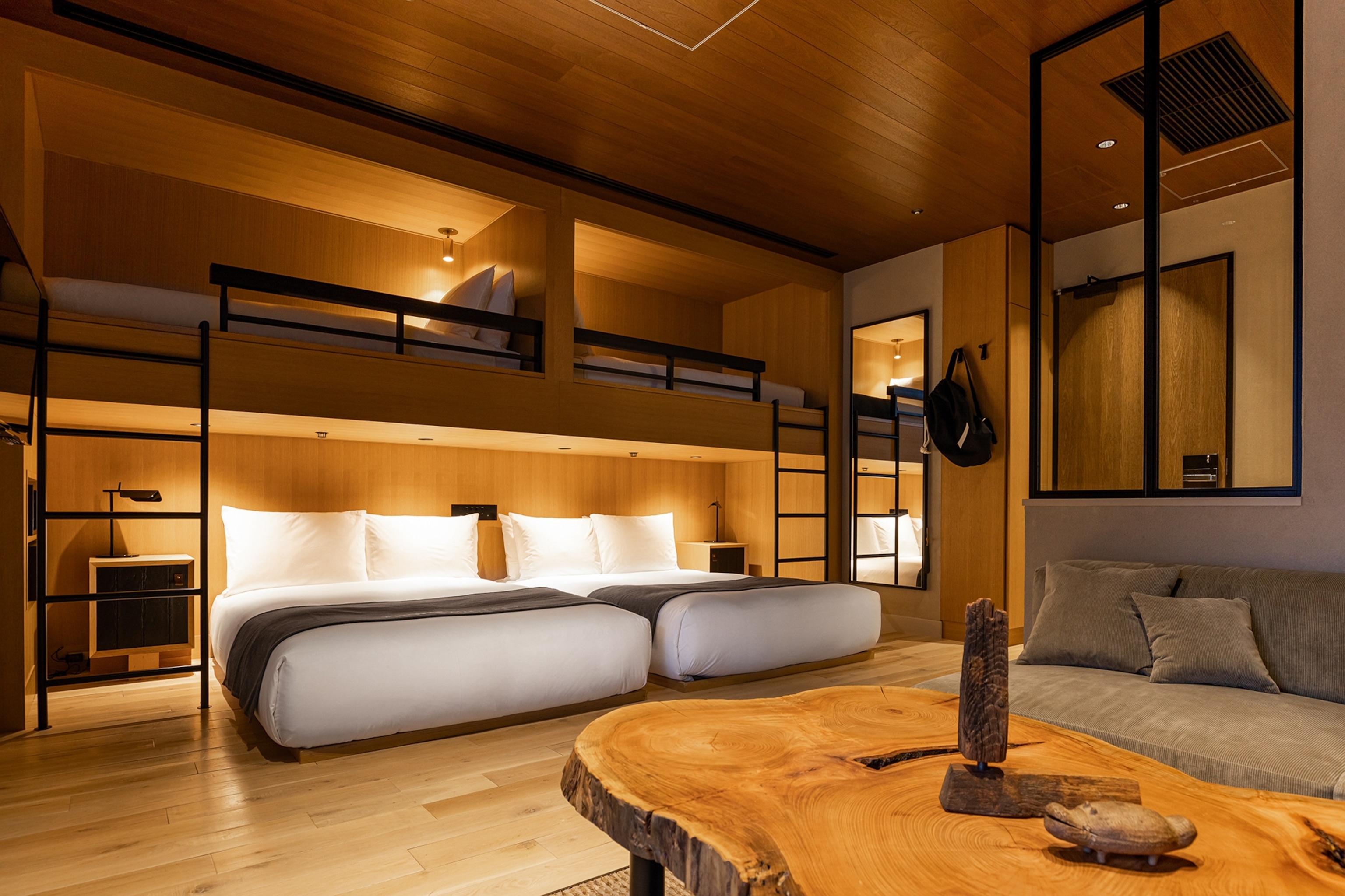 A balcony junior room at Trunk Hotel, with dimmed lights, a wooden interior and large double beds.